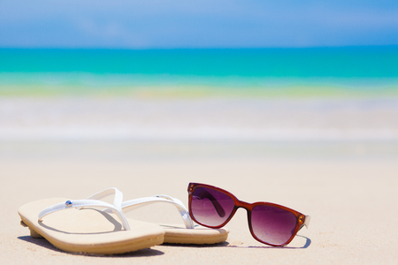 flip flops, heart-shaped sunglasses and frangipani on tropical beachの写真素材