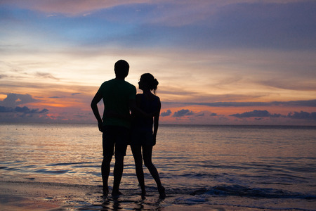 sunset silhouette of young couple in love at beachの写真素材