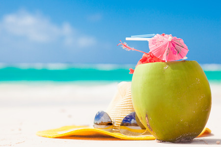 picture of fresh coconut cocktail and blue sunglasses on tropical beach