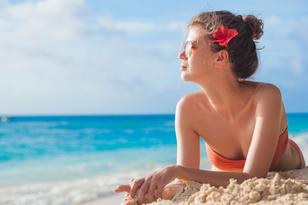 portrait of woman in sunglasses with hibiscus flower in her hair at beach. La Digue, Seychelesの写真素材