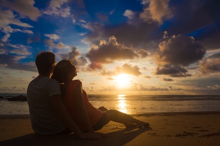 sunset silhouette of young couple in love hugging at beachの写真素材