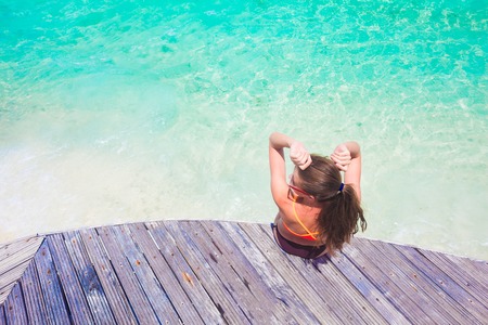 pretty woman in swimsuitrelaxing with cocktail at wooden bridge by the beach. Maldivesの写真素材