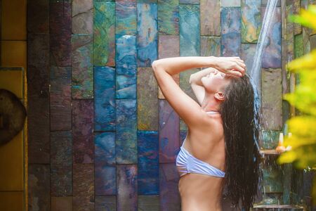 young woman refreshing in tropical outside showerの写真素材