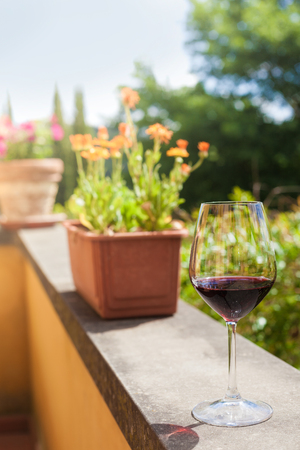 glass of chilled red wine on table over Tuscany backgoundの写真素材