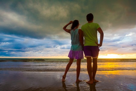sunset silhouette of young couple in love hugging at beachの写真素材