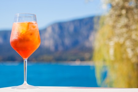 Glass of delicious Aperol Spritz cocktail on blurred mountains background