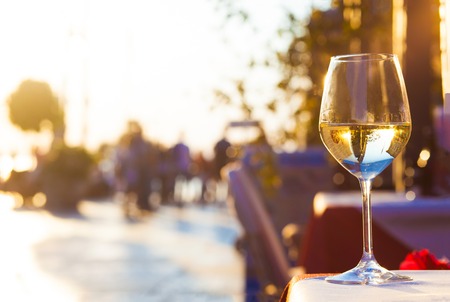 Glass of chilled white wine over sunset city backgroundの写真素材