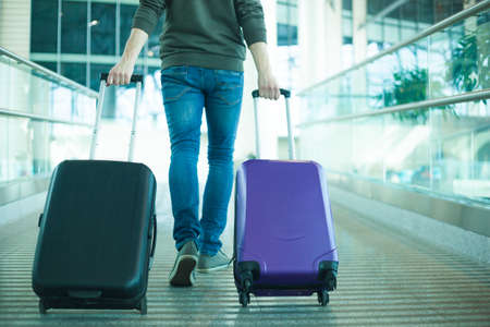 leg view of a man in hurry with cabin size bag in airportの写真素材