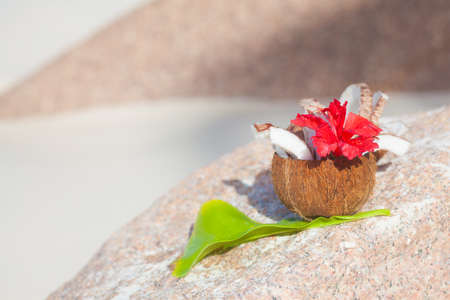 Summer exotic cocktail in fresh green coconut with colorful flower on tropical background