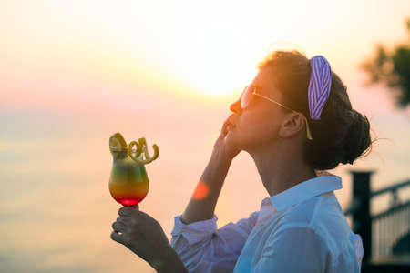 Woman drinking a cocktail over looking the ocean