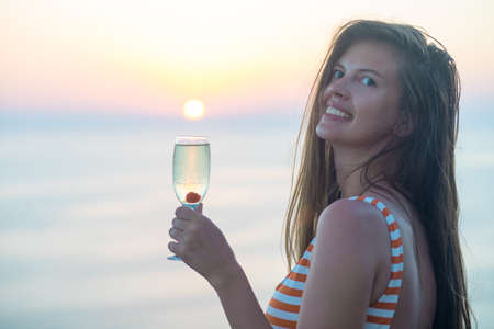 Woman drinking a prosecco over looking the oceanの写真素材