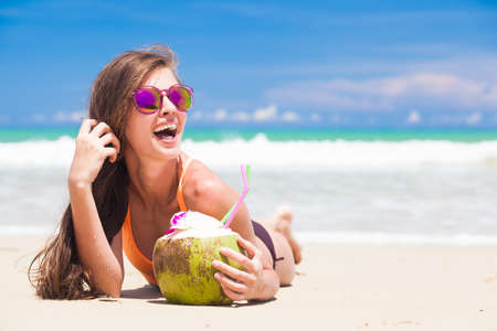 beautiful longhaired woman in sunglasses drinking coconut cocktail by the beachの写真素材