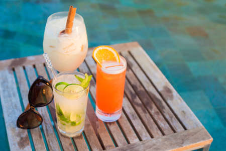 three perfect cocktails pina colada, sex on the beach and mojito, pool backgroundの写真素材