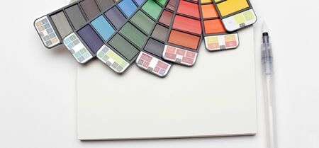Watercolor paint rainbow palette with brush on white texture paper. Flat lay.  Top view.. Horizontal long banner.の写真素材