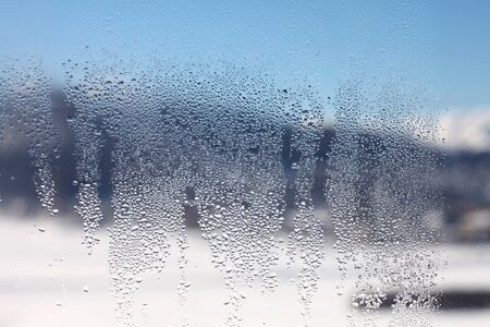 Water drop on glass. Window with blur winter snow landscape.の写真素材