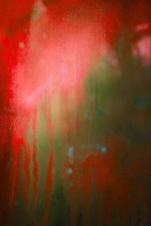 Old dirty dusty window glass with mystical reflection. Soft focus.  Abstract background with scratches. Red and green olor. Dusty artifacts.の写真素材