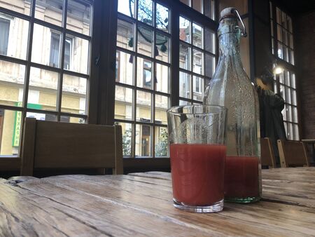 Homemade tomato juice in bottle and glass on  rough wooden table in cafe.の写真素材
