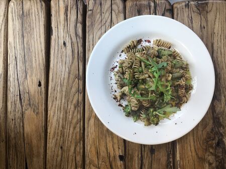 macaroni Nutty Fusilli (Italian pasta) with chicken, vegetables, Arugula and pesto sauce rough wooden table.  Gluten free dish. Flat lay. Top view.の写真素材