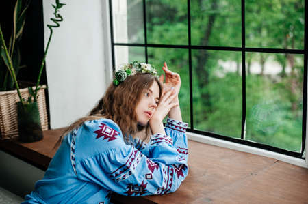 A girl in traditional Ukrainian clothes is lying on the windowsillの写真素材