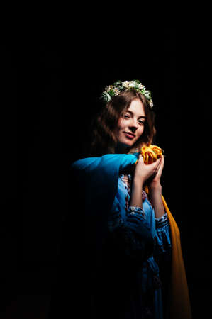 A girl on a black background in traditional Ukrainian clothes stands with the flag of Ukraineの写真素材