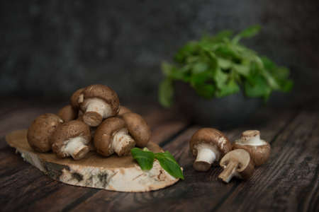 Royal mushrooms on a birch plank with a cup of greenery in the background