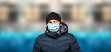 man in blue protective medical mask in the city against the background of the bridge and skyの写真素材
