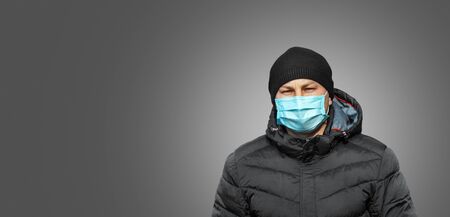 man in blue protective medical mask in the city on a gray backgroundの写真素材