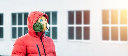 man in a gas mask and a hood on the background of windowsの写真素材