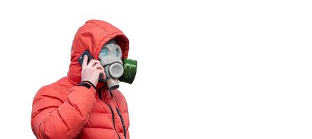man in a gas mask and a hood holding a phone in his hands on a white backgroundの写真素材
