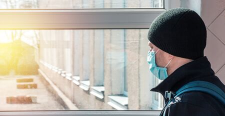man in a medical mask on a background of windowsの写真素材