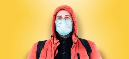 man in a medical mask and a hood on a yellow backgroundの写真素材