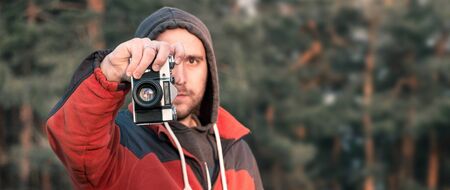 man takes pictures on an old mechanical camera on a background of natureの写真素材
