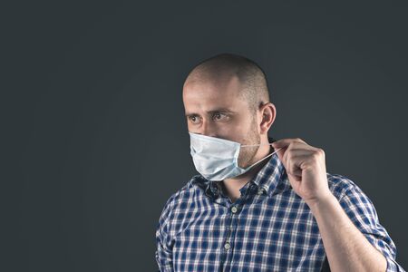 young man in blue protective medical mask on a dark backgroundの写真素材