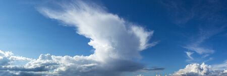 large rain clouds in broad daylight over a small townの写真素材