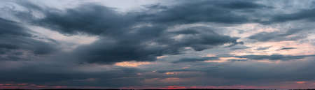 Dark sunset with gloomy clouds and red light on the horizon