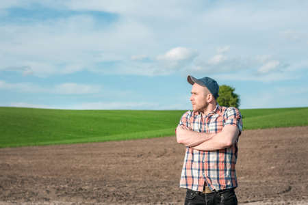 A male agronomist examines wheat crops in an agricultural field. A farmer in a wheat field makes notes in a notebook. Grain crop yield assessmentの写真素材