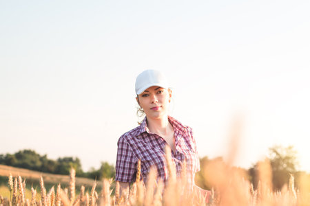 Young woman farmer works on a wheat field in the sun. Business woman plans her income in the field. Female agronomist with a tablet study the wheat crop in the agricultural field. Grain harvest.の写真素材