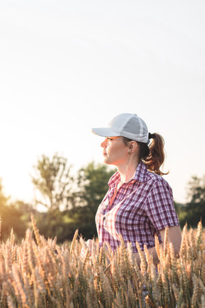 Young woman farmer works on a wheat field in the sun. Business woman plans her income in the field. Female agronomist with a tablet study the wheat crop in the agricultural field. Grain harvest.の写真素材