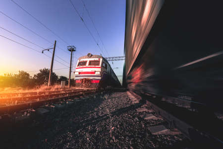 Old suburban train on the background of a moving freight train in the morning