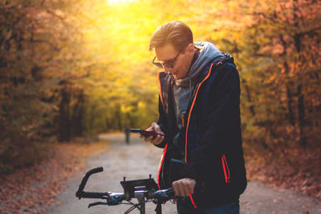 Man on a bike in the autumn forest in the evening at sunsetの写真素材