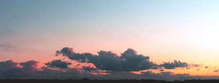 Gray clouds illuminated by the sun on a gradient sky background