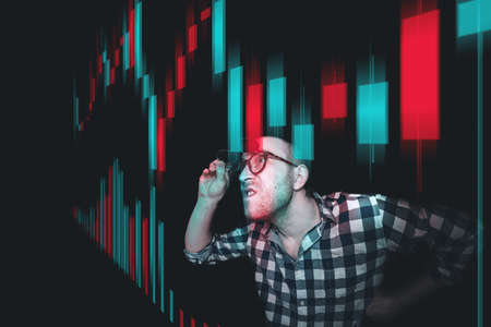 A trader-investor is watching the price movement on the screen with emotions. Analyzes the financial holographic chart of quotes. Comic image of a trader-investor.の写真素材
