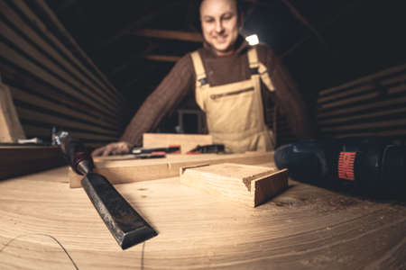 A man makes wood products with the help of special tools. Portrait of a young carpenter at work. Employment in the woodworking industryの写真素材