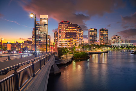 West Palm Beach, Florida, USA. Cityscape image of West Palm Beach, Florida with bridge leading to the downtown and reflection of the city skyline in the water at beautiful sunset.の写真素材