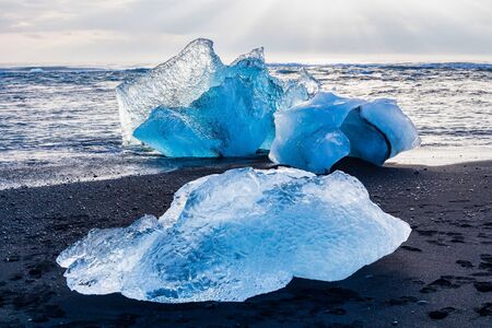 Iceberg at Diamond Beach Joekulsarlon. Blue chunk of ice on the black sand beach near the Glacier...