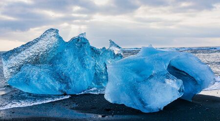 Iceberg at Diamond Beach Joekulsarlon. Blue chunk of ice on the black sand beach near the Glacier...