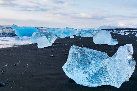 Iceberg at Diamond Beach Joekulsarlon. Blue chunk of ice on the black sand beach near the Glacier...