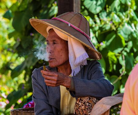 Heho, Myanmar - Nov 08, 2019: Smoking woman at a market in the city center of Heho in Myanmar, former Burma in Asiaのeditorial素材