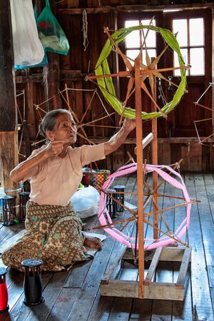 Inle Lake, Myanmar - Nov 09, 2019: Woman of Padaung tribe, Karen long-necked tribe weaving textile scarfのeditorial素材
