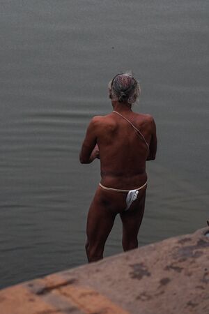 Varanasi, India - Dec 26, 2019: Hindu taking ritual bath in the river Ganga in the holy city of Varanasi, India. The holy ritual bath is held every day.のeditorial素材